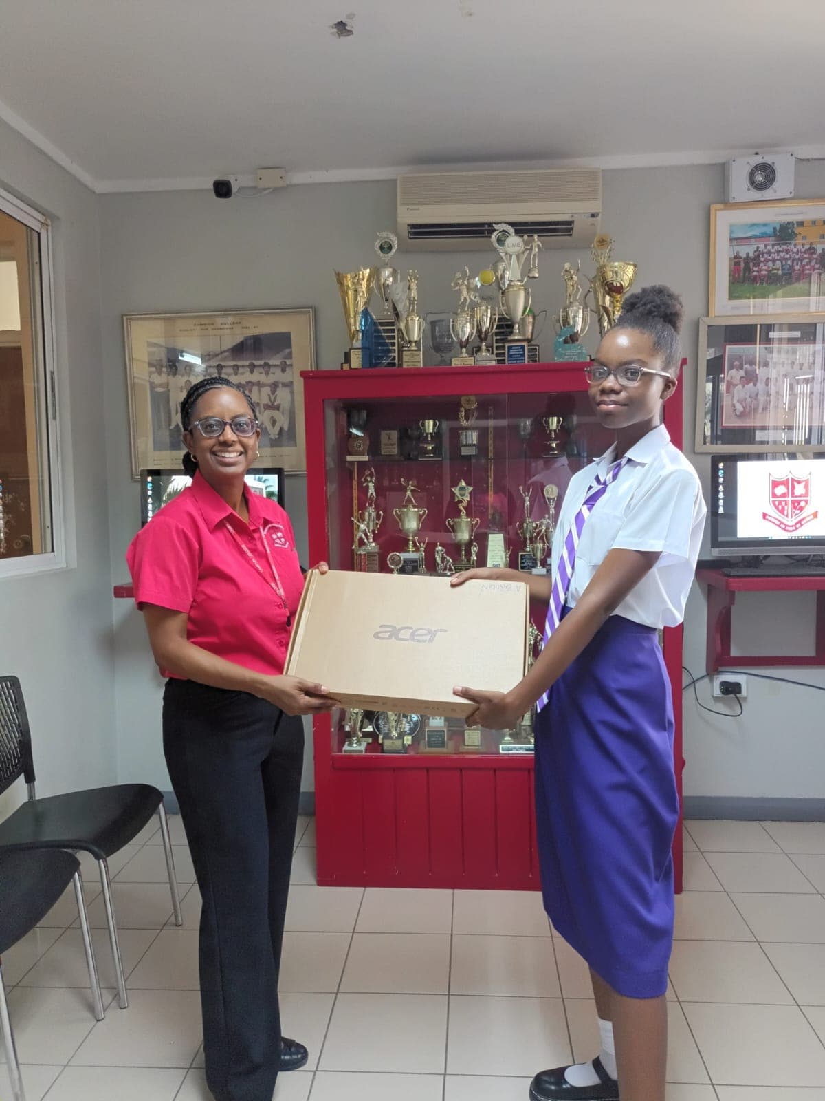 A Campion College student in uniform accepting a boxed laptop from a member of staff.