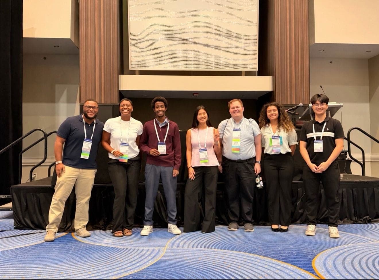 Stefen Ewers with his team at the Tapia Conference: seven people in conference lanyards standing in front of the main stage.